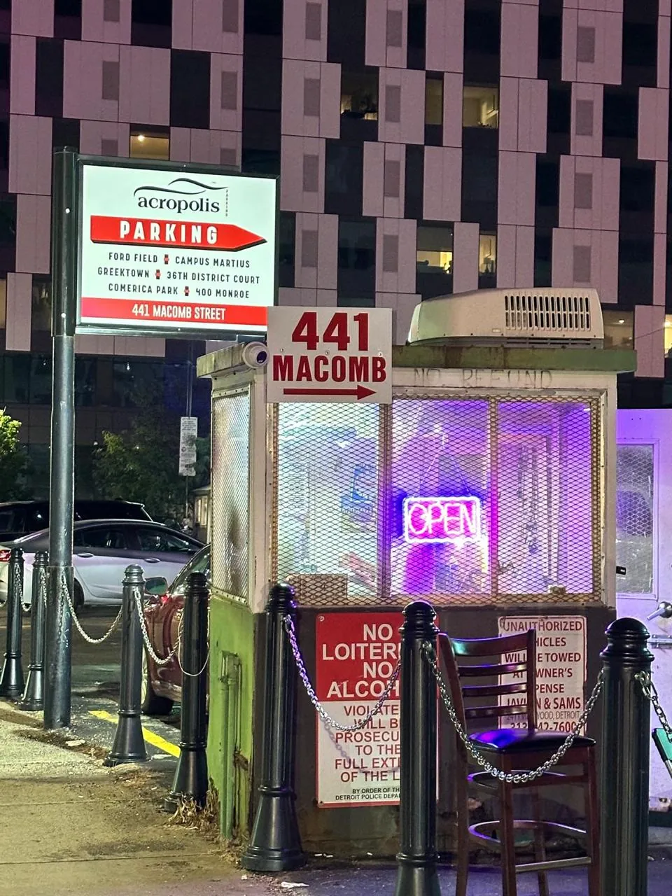The Acropolis Parking booth and sign at 441 Macomb St, lit up at night